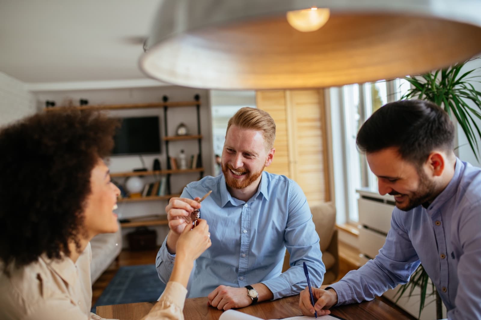 An estate agent handing over keys to a smiling couple across a table